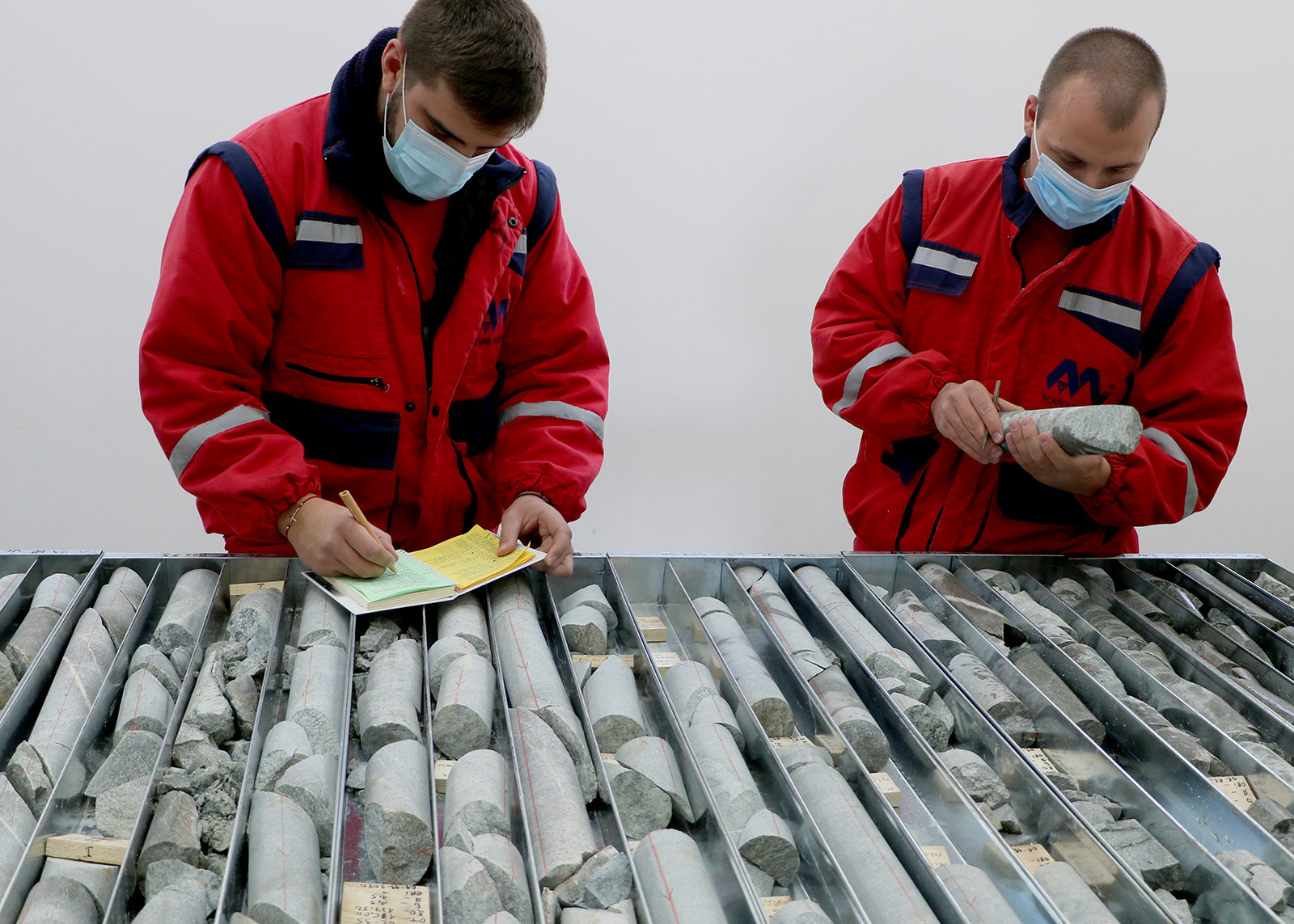 Geologists in red jumpsuits, analysing copper core
